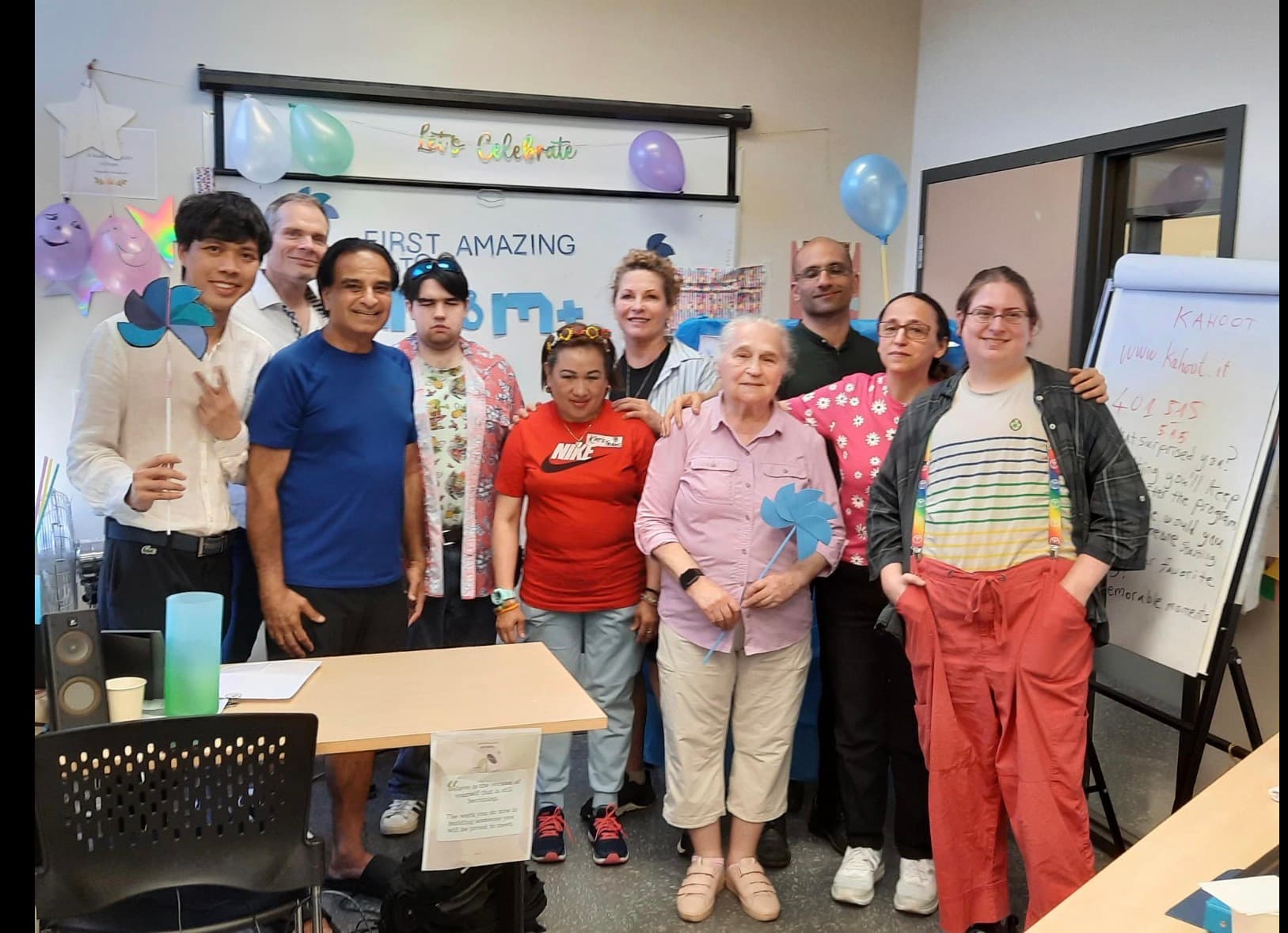 A community group gathering in a classroom with decorations and blue pinwheels